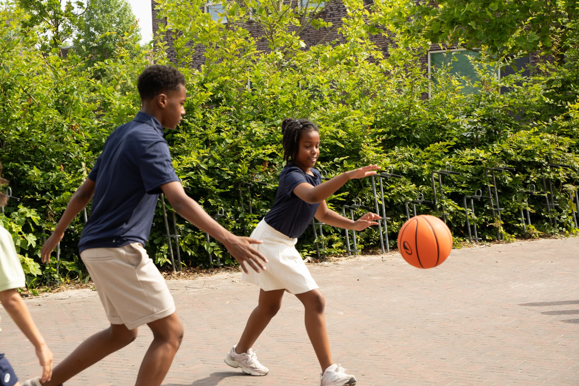 Leerlingen spelen samen basketbal op het schoolplein