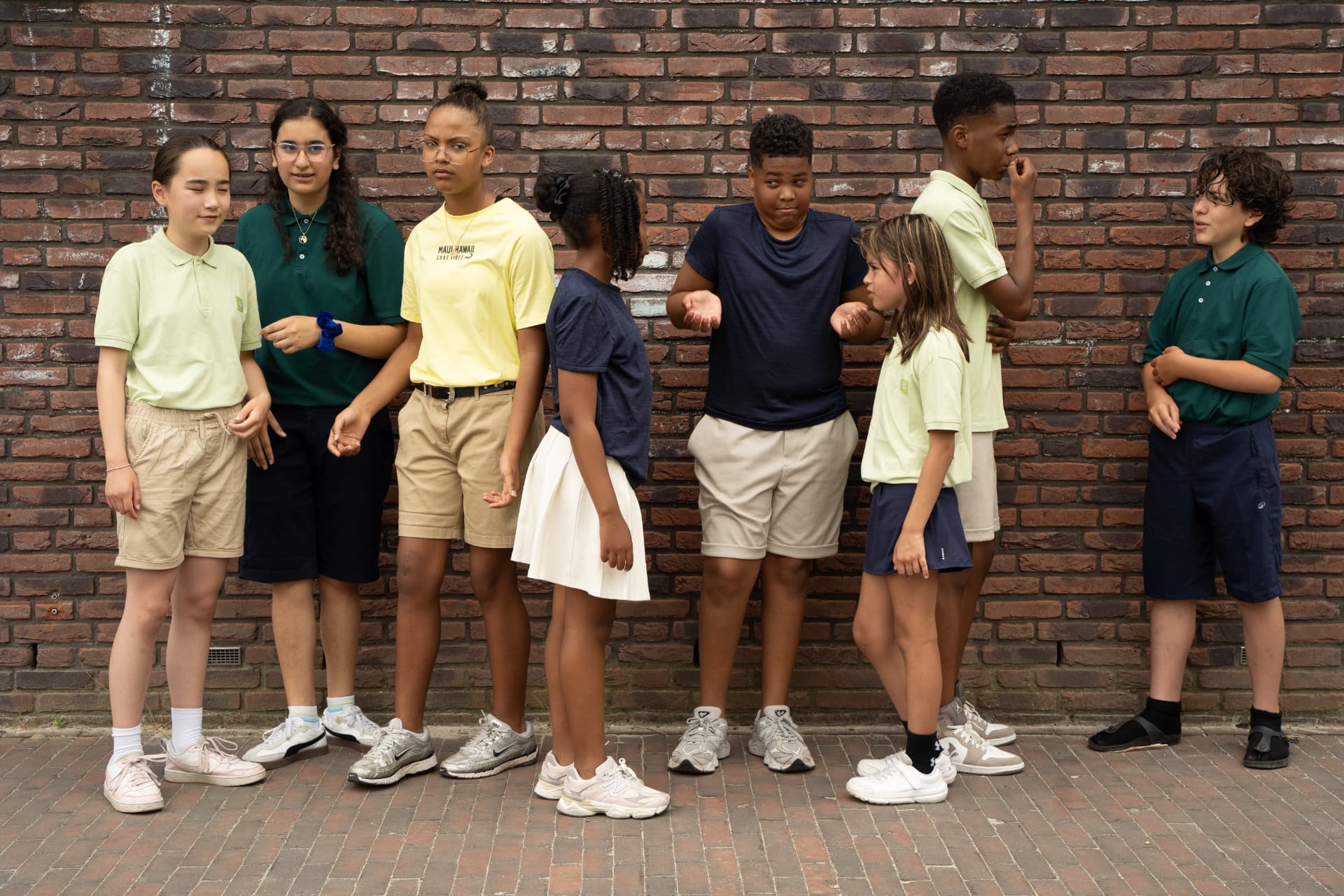 Leerlingen staan samen langs de muur van de school